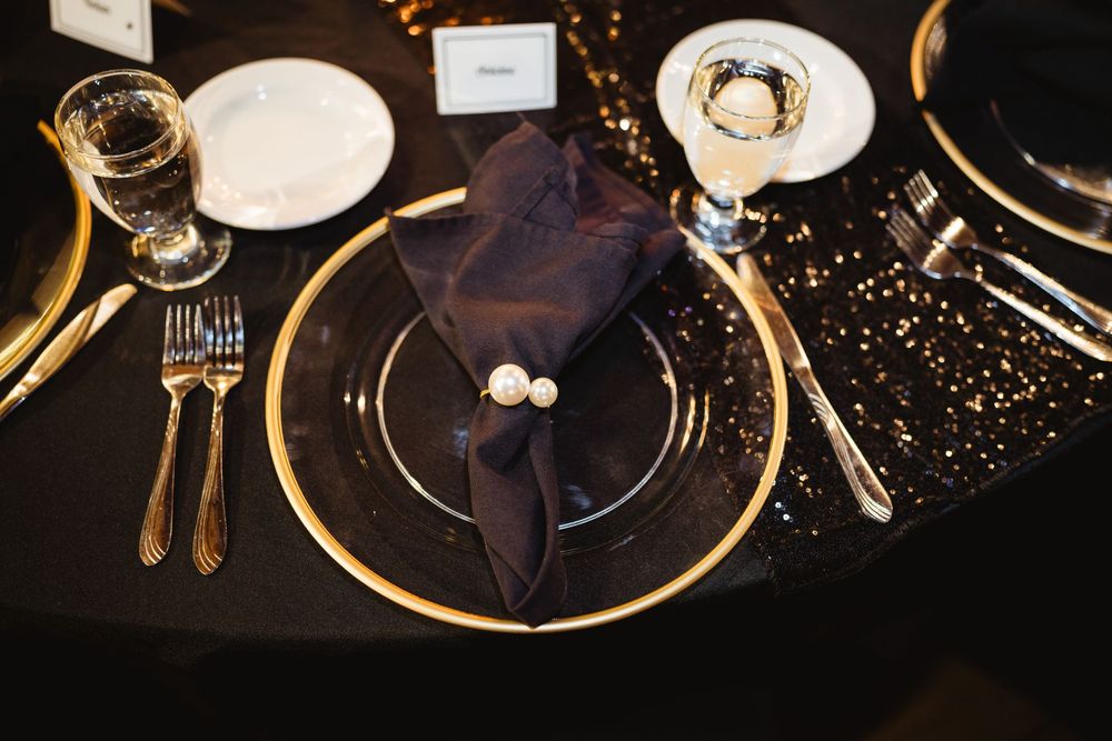 Elegant black and gold place settings with glittering details at a formal dinner event.