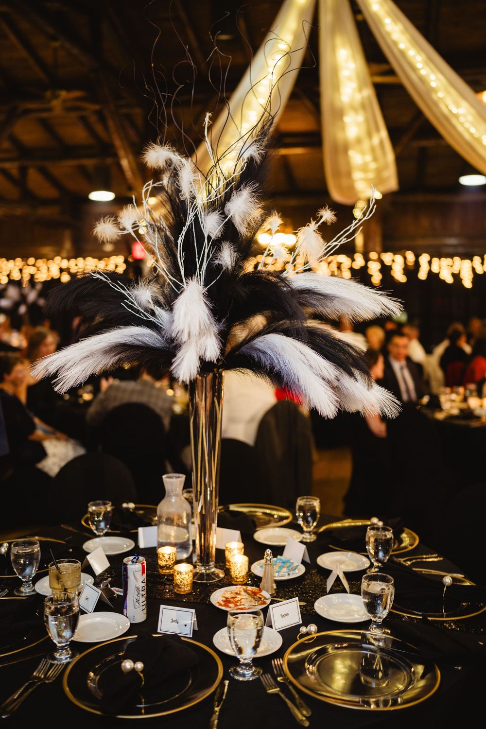 Luxurious table decorations featuring white feathers and gold accents at an evening reception.