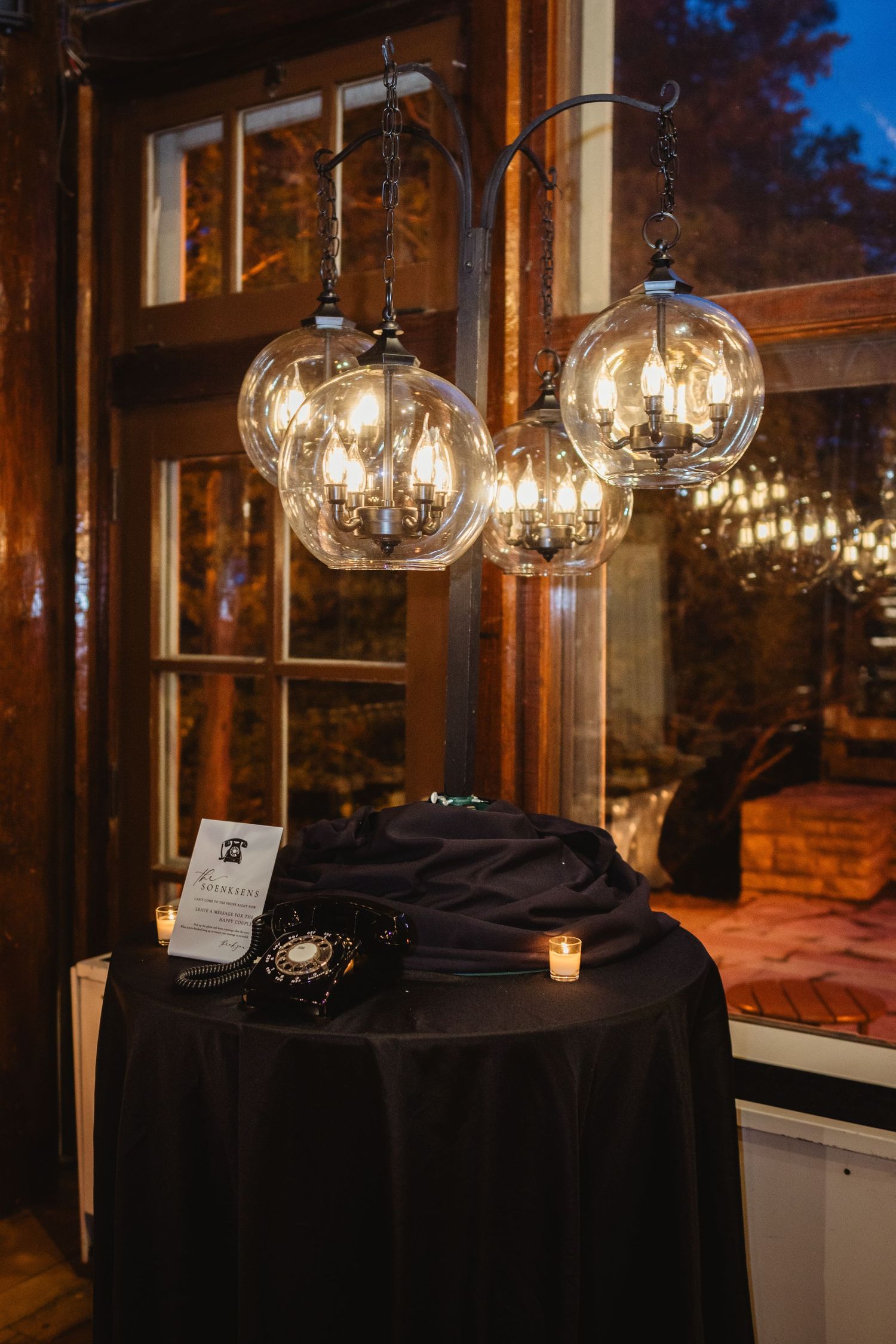 Glass globe pendant lights hang over a black tablecloth-covered table in an elegant evening venue setting.