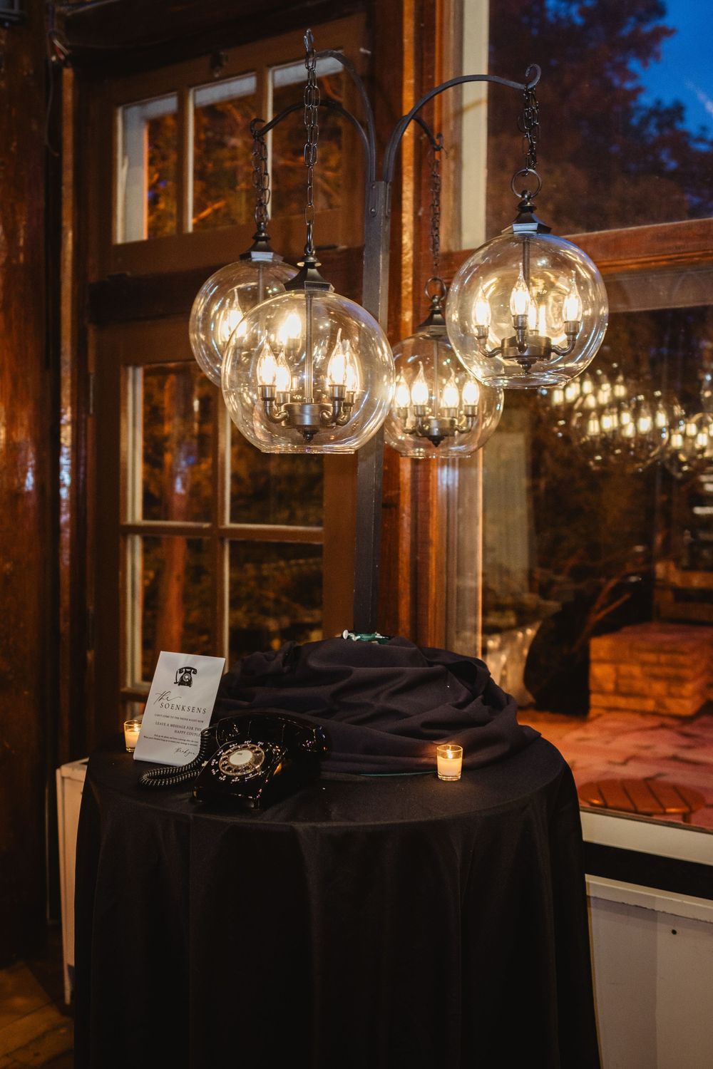 Glass globe pendant lights hang over a black tablecloth-covered table in an elegant evening venue setting.