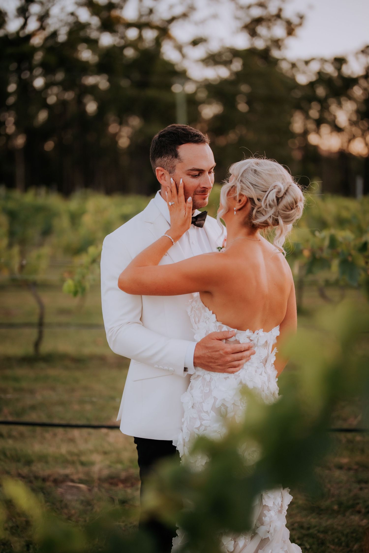 A couple shares an intimate dance together outdoors at sunset in a vineyard setting.