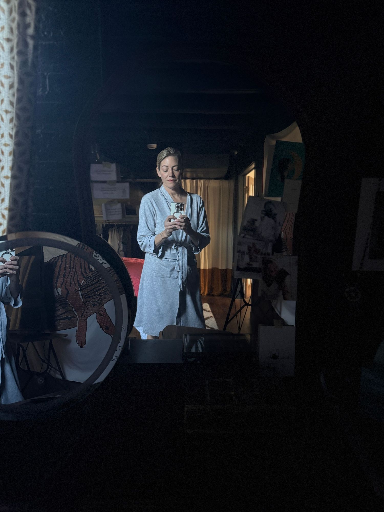 A person in a white shirt stands in a dimly lit room with reflective surfaces creating a mirror-like effect.