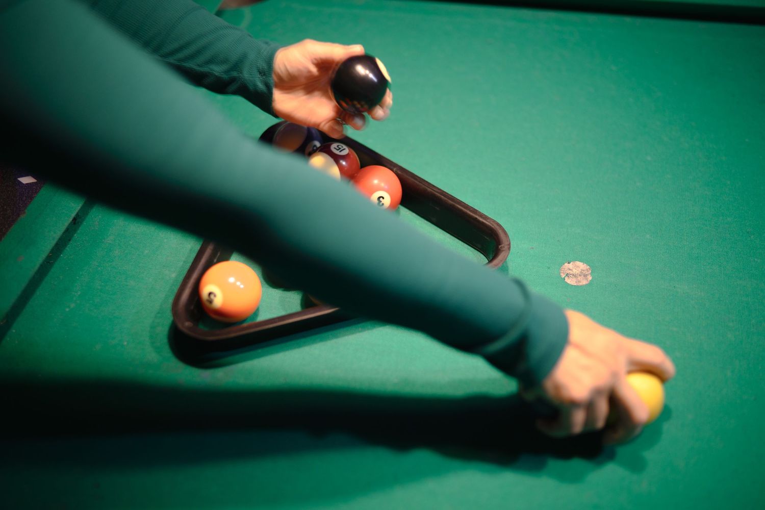 Close-up of hands lining up a shot on a green pool table.