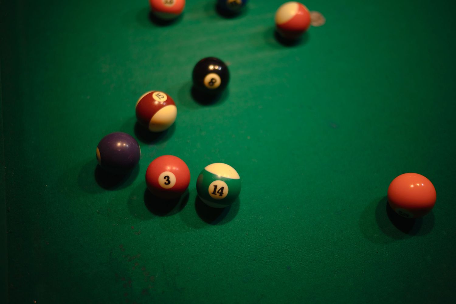 Colorful billiard balls scattered on a green felt pool table surface.