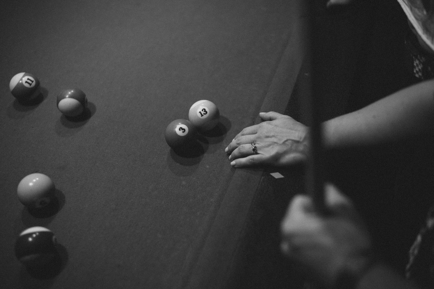 Black and white artistic shot of billiard balls and cue stick on a pool table.