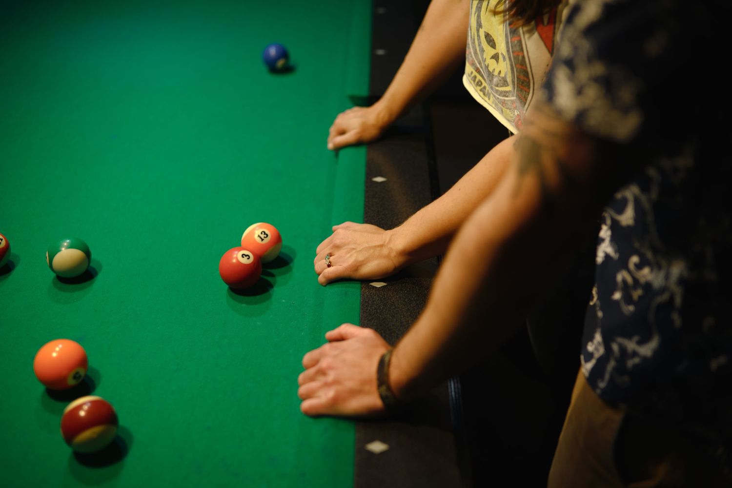 Hands holding pool cues hover over a green billiards table during gameplay.