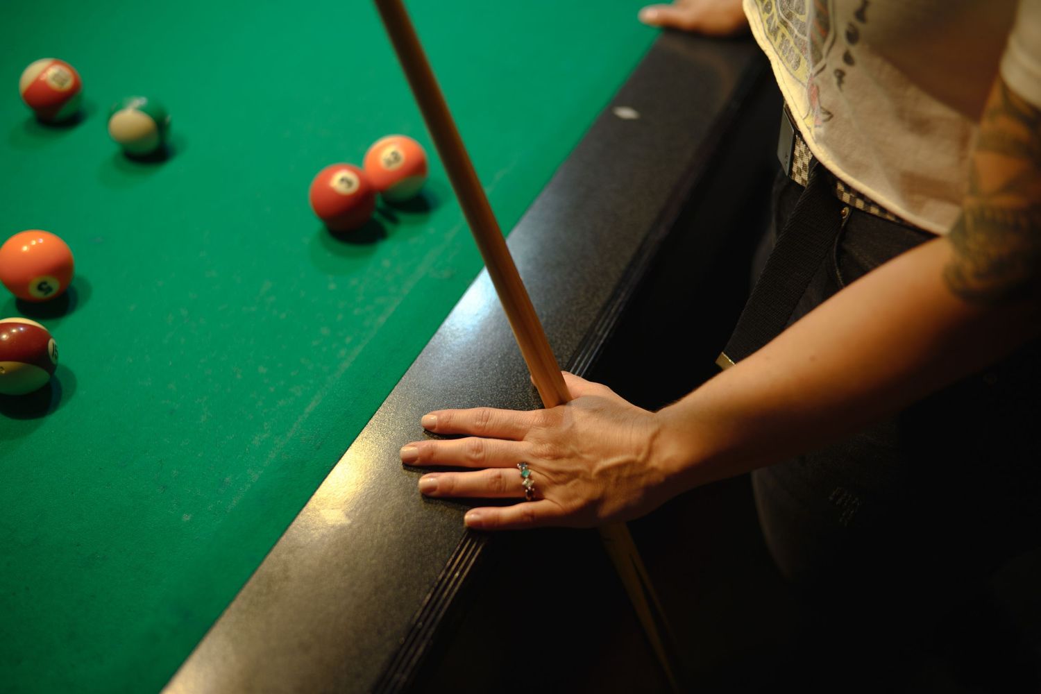 Players line up shots on a green pool table with red and white balls visible.