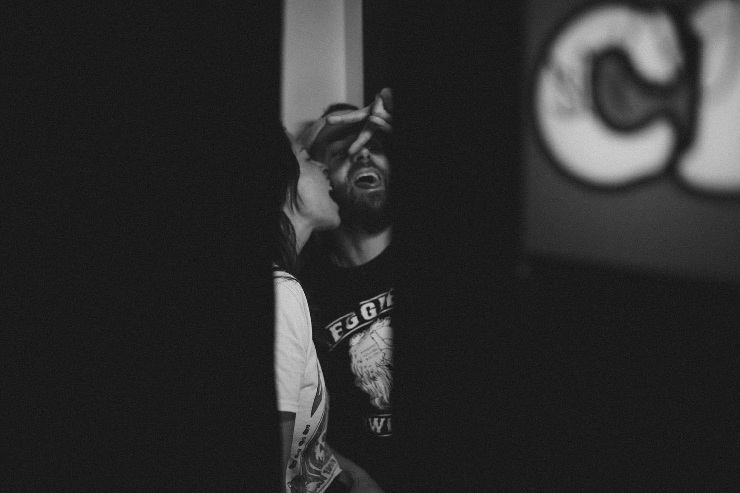 Dramatic black and white portrait of a person wearing a cap in low light.