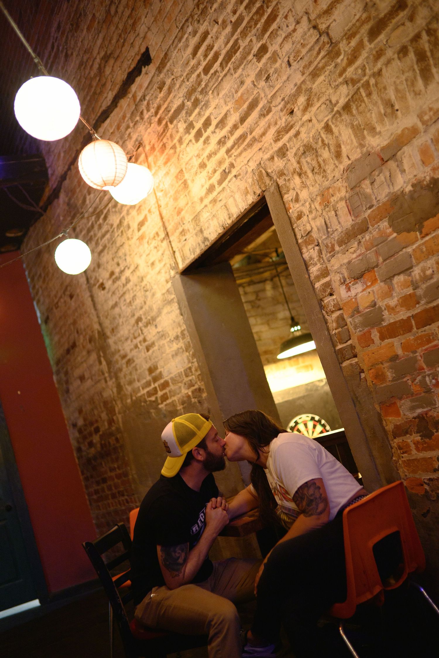 Exposed brick wall interior of a bar with hanging globe lights creating ambient atmosphere.