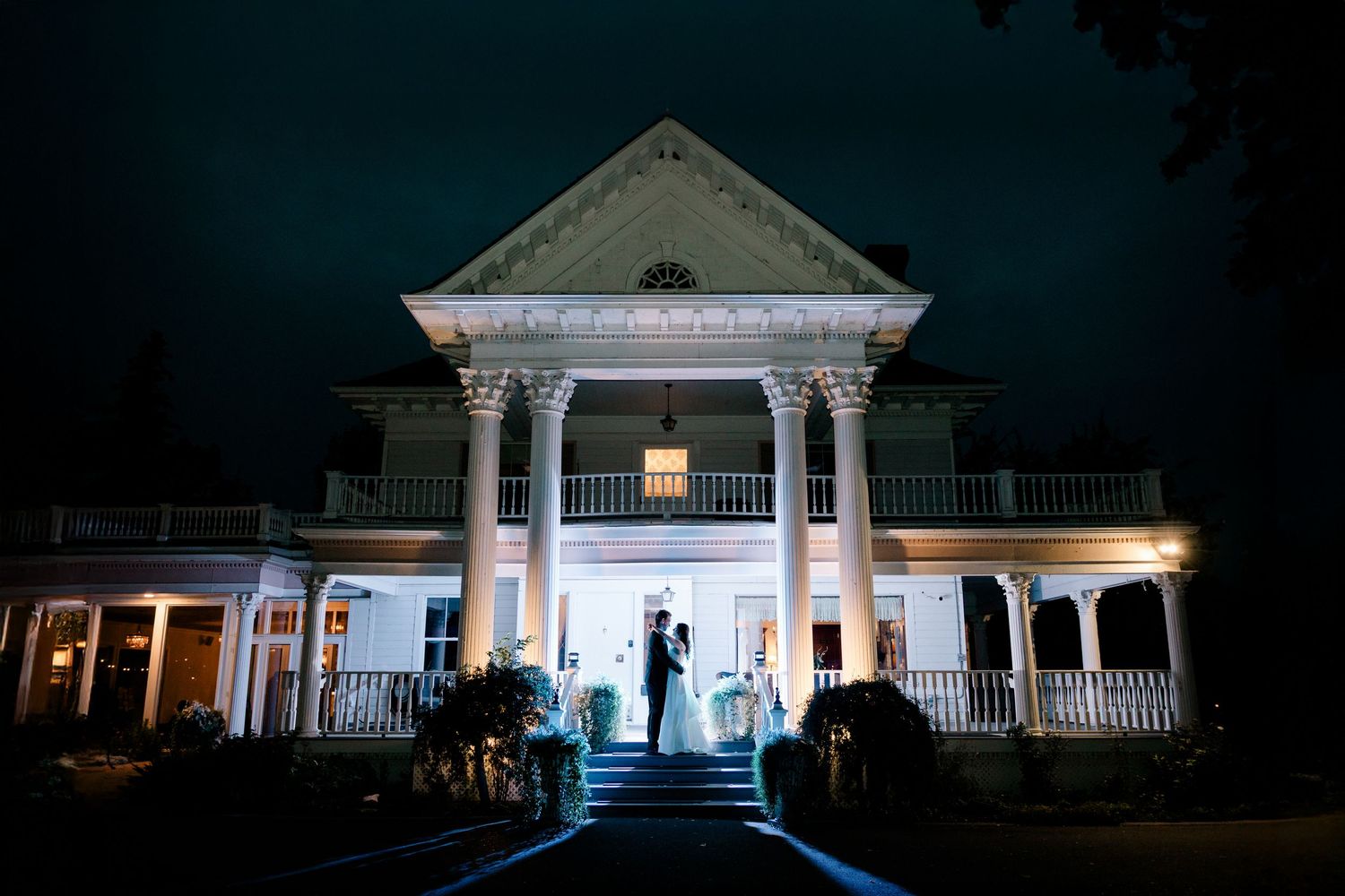 A series of illuminated white gazebos and porches at night creating a romantic architectural display.