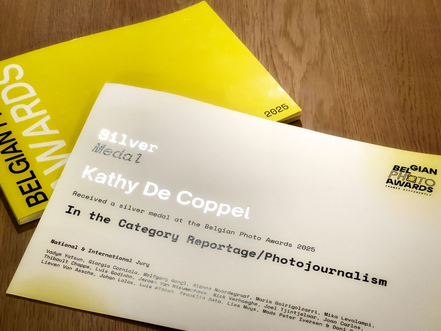Yellow paper documents and business cards scattered on a wooden surface.