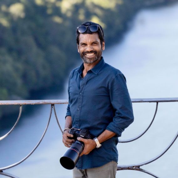 Professional photographer working with camera equipment near a waterfall vista.