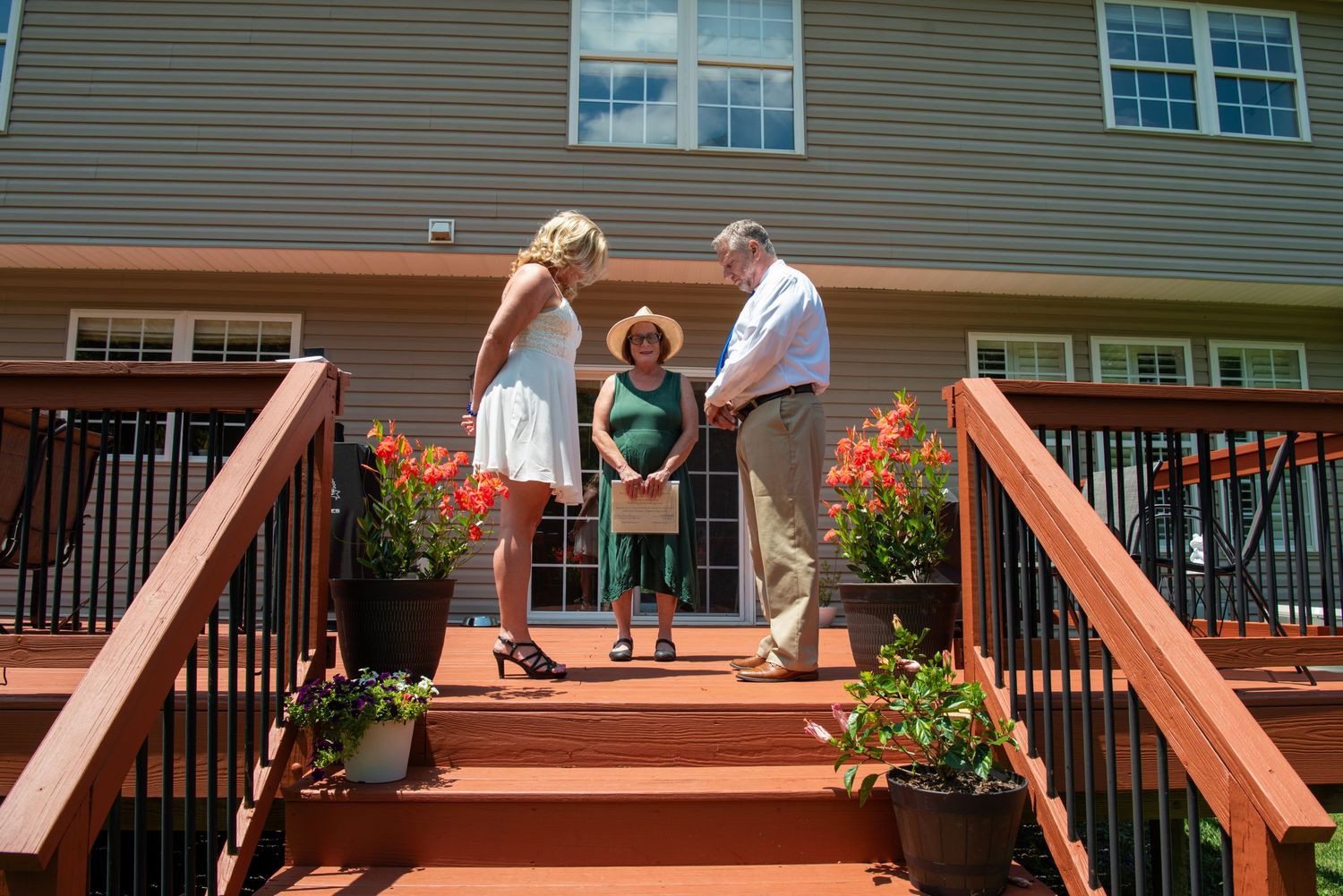 Wooden deck railing posts installed along a residential patio with decorative angled supports and flower planters.