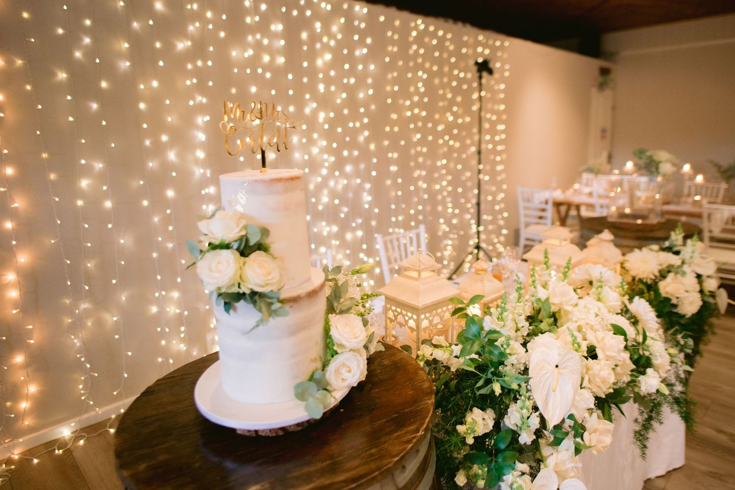 A panoramic view of a wedding reception venue with white draping, checkered dance floor, and ambient lighting.