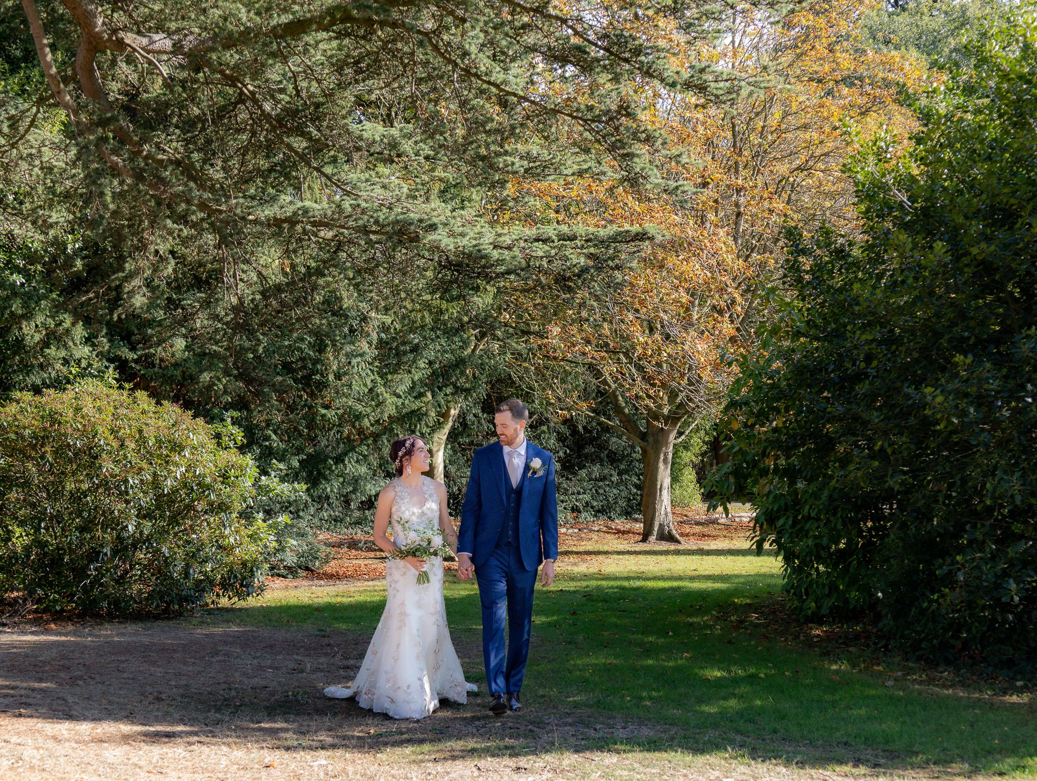 A couple walking together through a scenic autumn park during a wedding photoshoot.