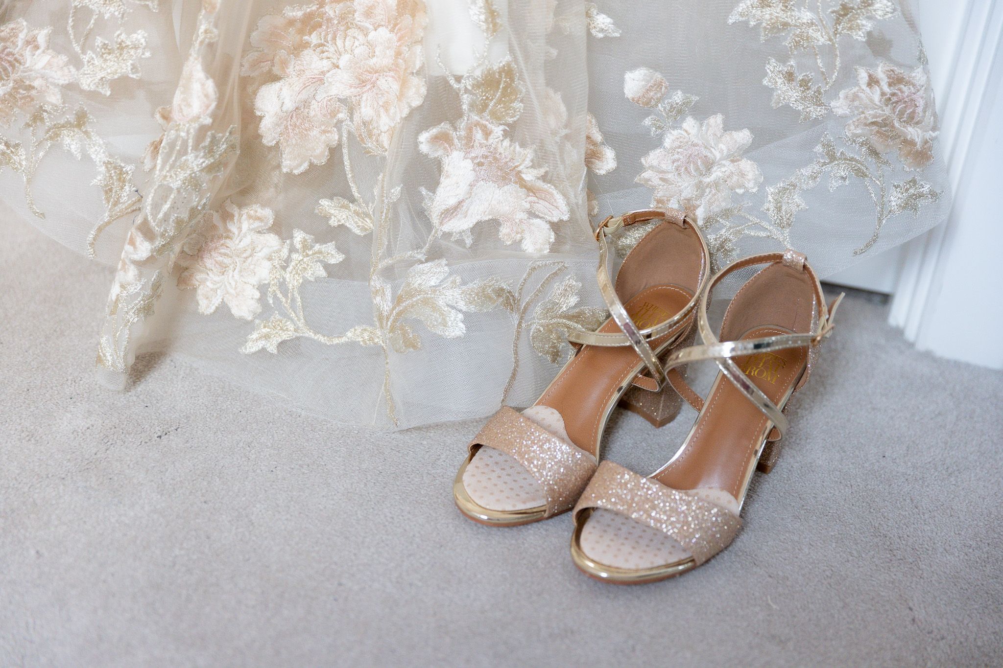 Elegant bridal shoes with crystal embellishments and ankle straps displayed in a row on white floor.