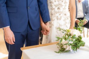 Wedding party members in navy blue suits and light colored dresses pose together in an elegant venue setting.