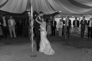 Wedding guests dance and celebrate under an elegant draped tent ceiling during an outdoor reception celebration.