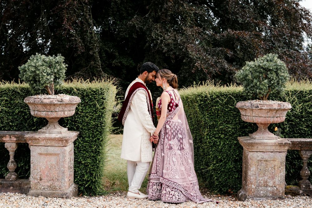 Jess and Pram’s British-Indian fusion wedding at Bredenbury Court Barns — bride in burgundy lengha, groom in white sherwani