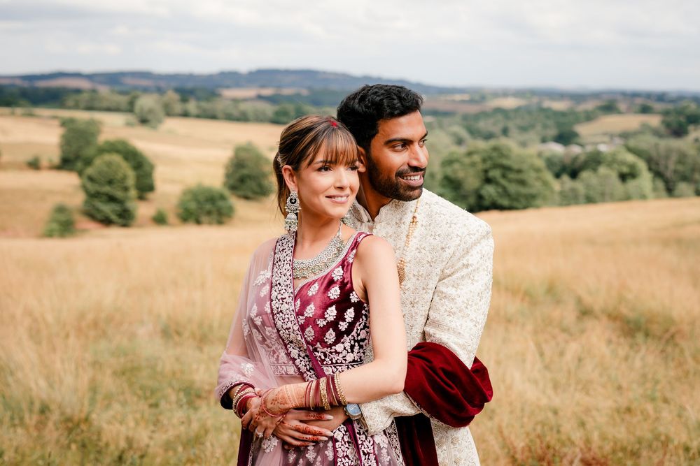 Jess and Pram’s British-Indian fusion wedding at Bredenbury Court Barns — bride in burgundy lengha, groom in white sherwani
