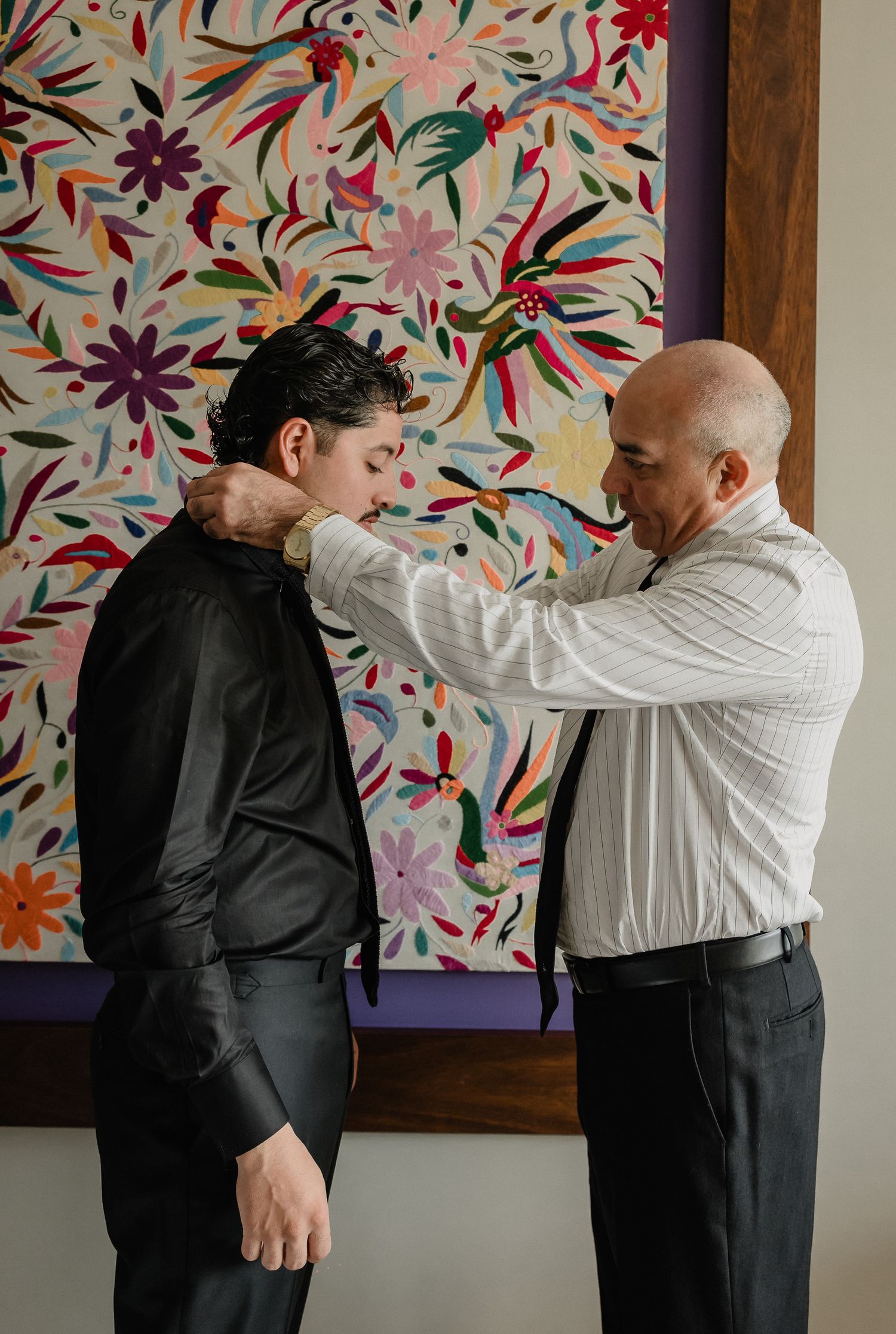 A sequence showing a man helping another adjust his tie against a colorful floral backdrop.
