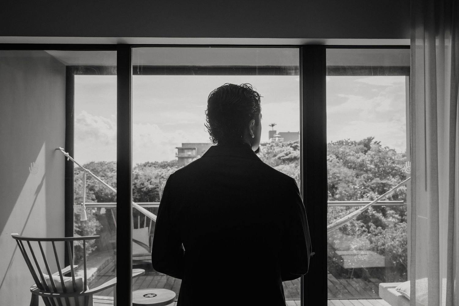 A silhouetted figure gazes out through large windows at a mountainous landscape.