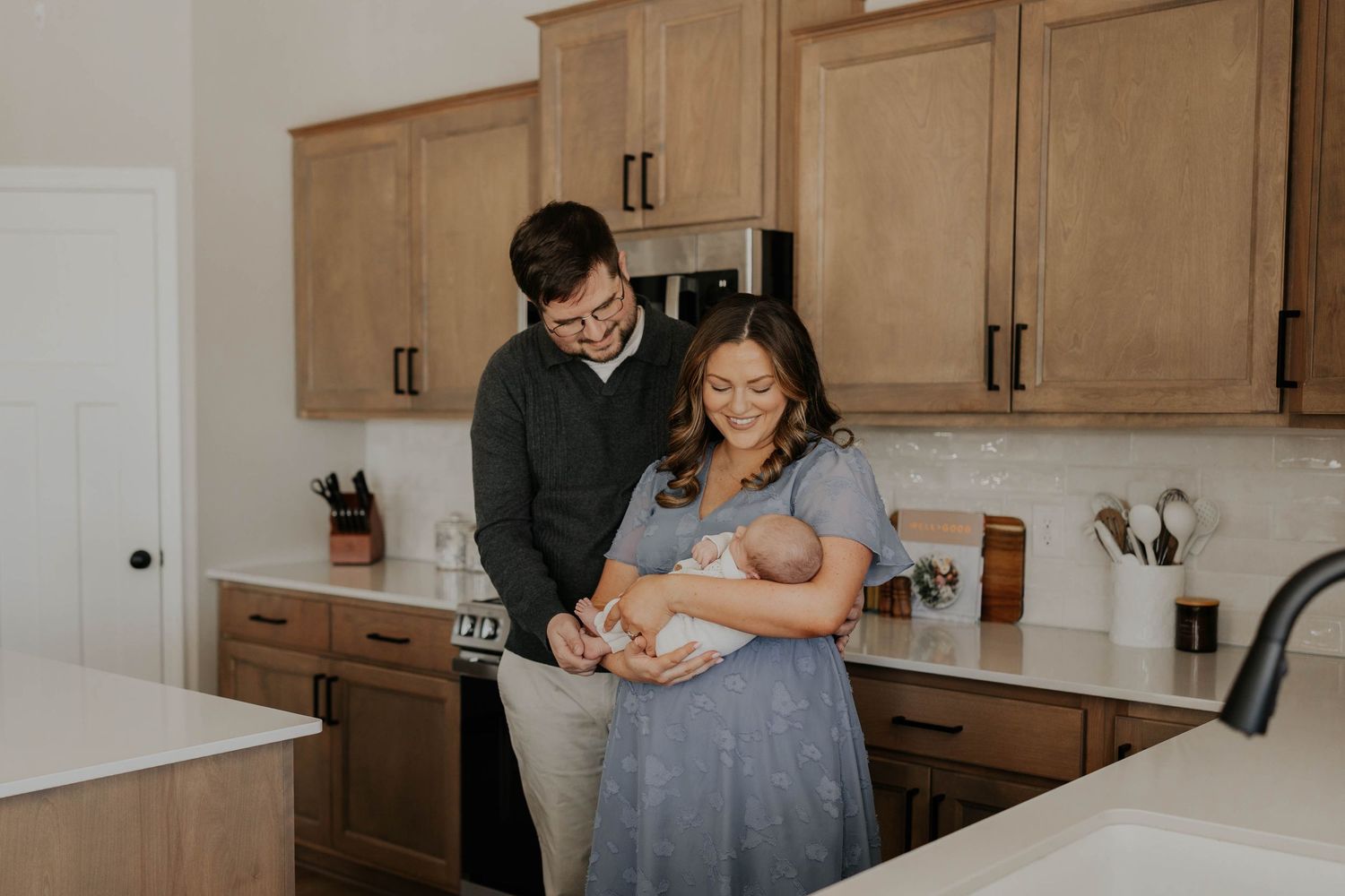 A family stands together in a cozy living room with natural window light in a warm, candid moment.