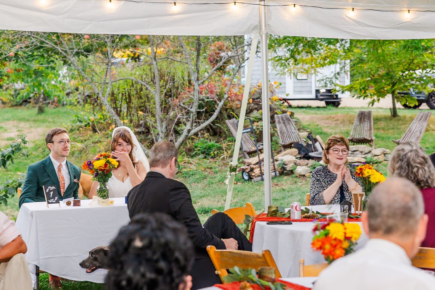 Outdoor wedding reception tables decorated with orange flowers and string lights creating a warm autumn ambiance.