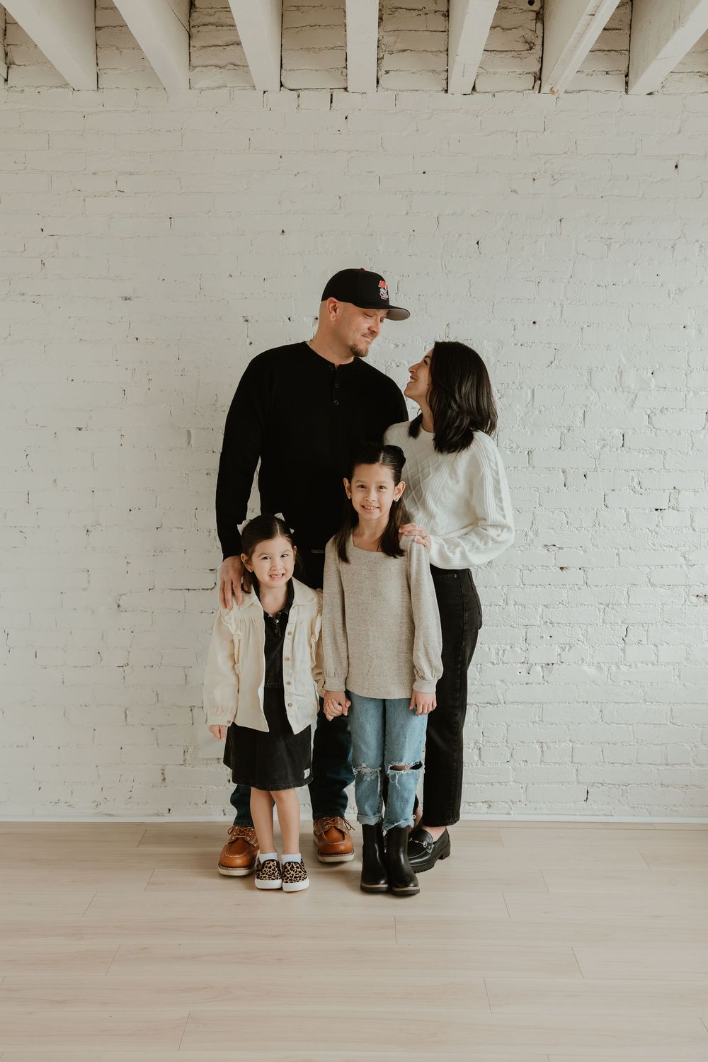 A minimalist family photoshoot sequence against a white brick wall showing tender moments and interactions.
