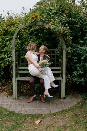 A romantic couple shares tender moments on a garden bench beneath a lush green archway in a series of photos.