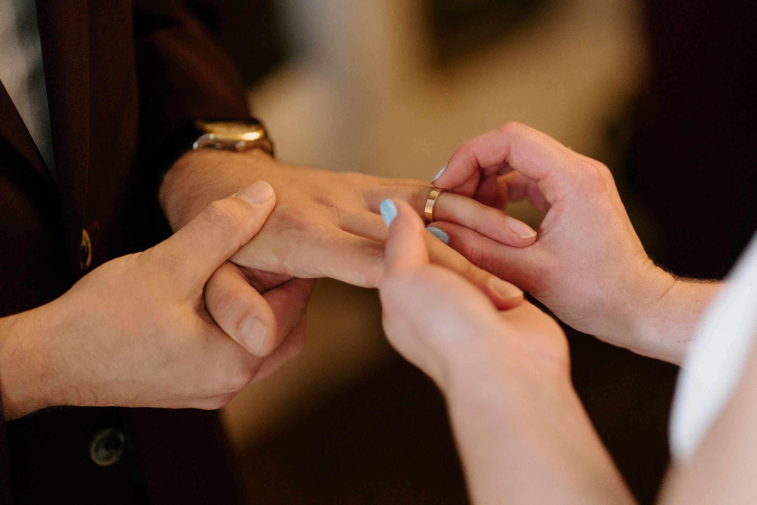 Close up of hands exchanging rings during a wedding ceremony.