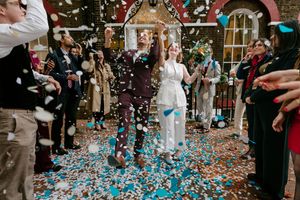 Wedding guests celebrate with confetti during a joyful reception at an indoor venue.