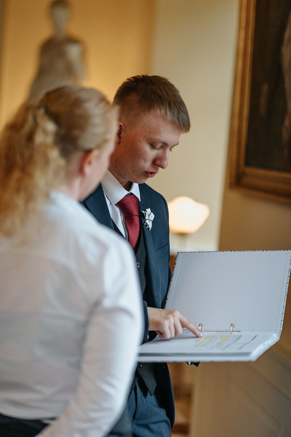 Wedding guests signing a guestbook at an elegant indoor venue with warm lighting.