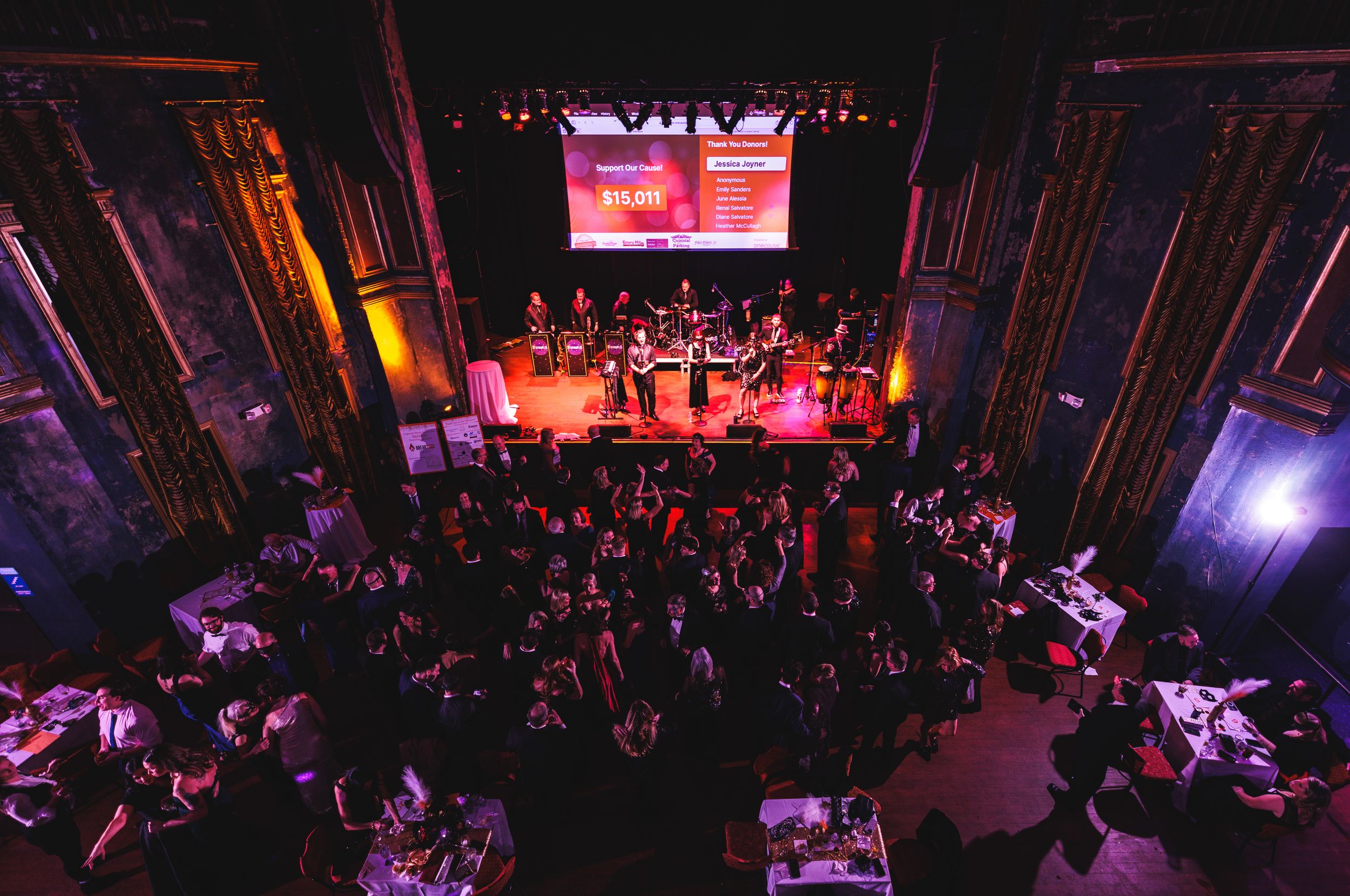 An aerial view of a concert venue with red stage lighting and crowd below.