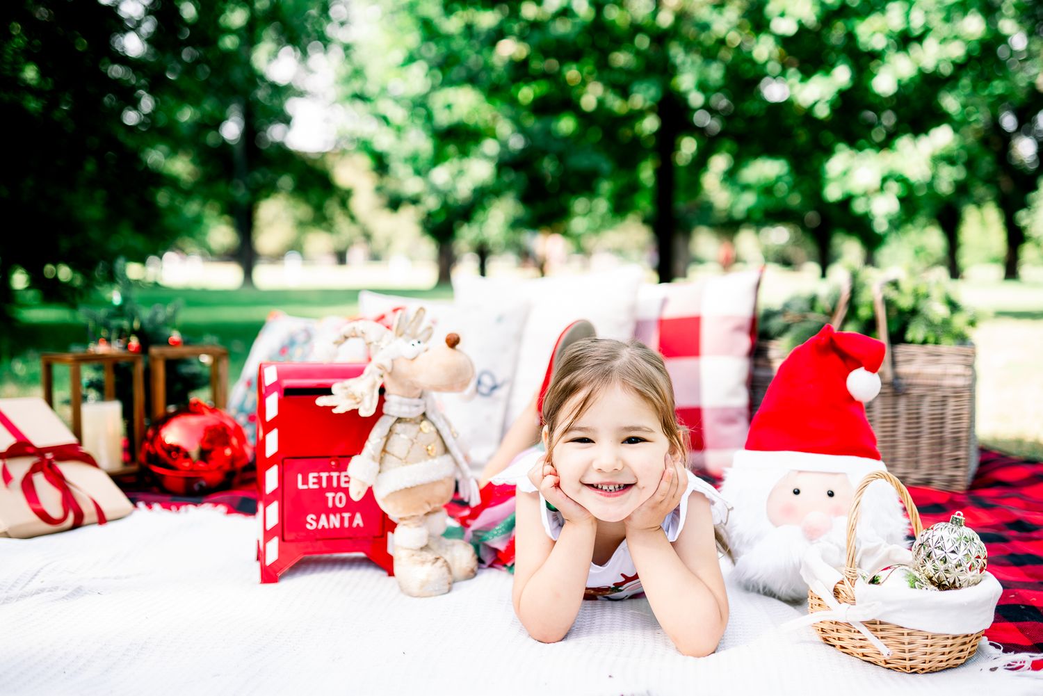 A child laying on a red and white checkered picnic blanket in a park during a Melbourne Christmas mini photo session in a park.