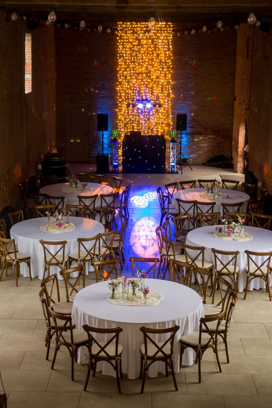 Wedding reception venue with elegant table settings and warm golden lighting display.