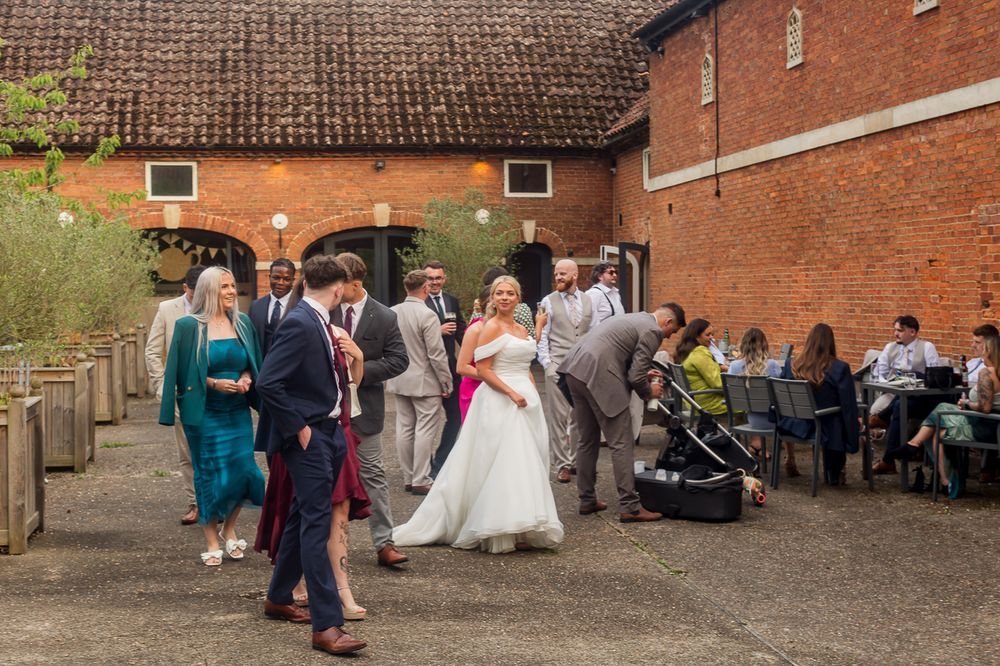 Outdoor brick venue with wedding guests mingling during reception celebration.