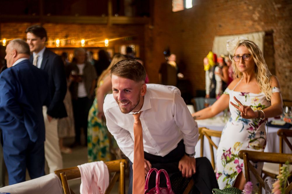 Wedding reception guests dancing and celebrating in a warmly lit brick venue.