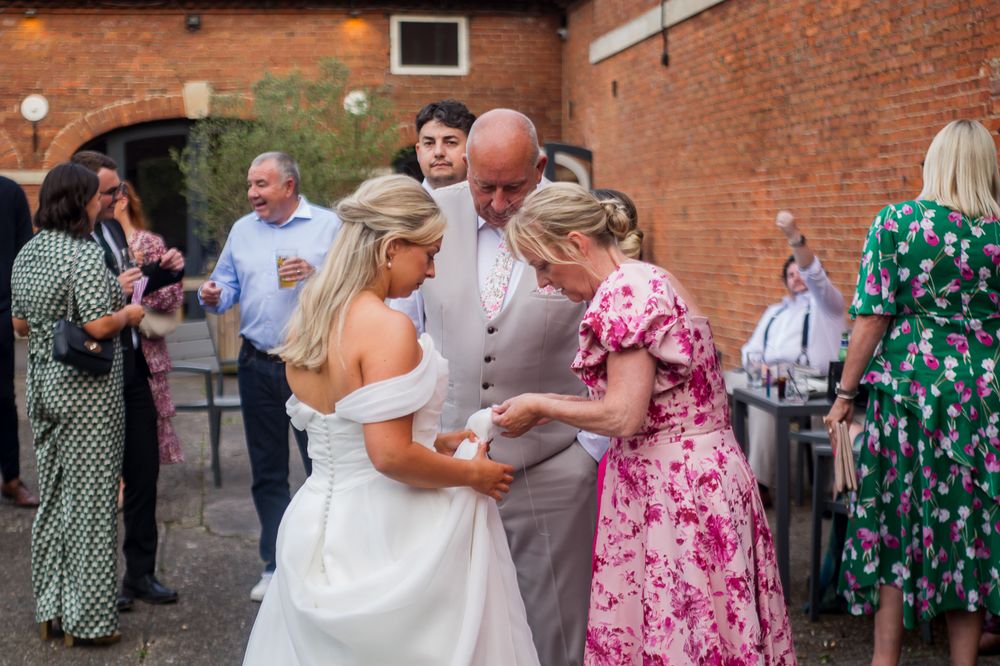 Wedding guests dancing and mingling outside a rustic brick building venue.