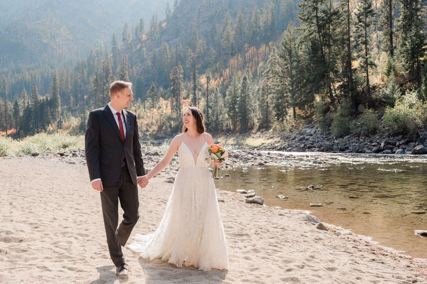 bride and groom walk alongside a river in Leavenworth. Photo by Washington Elopement Photographer.