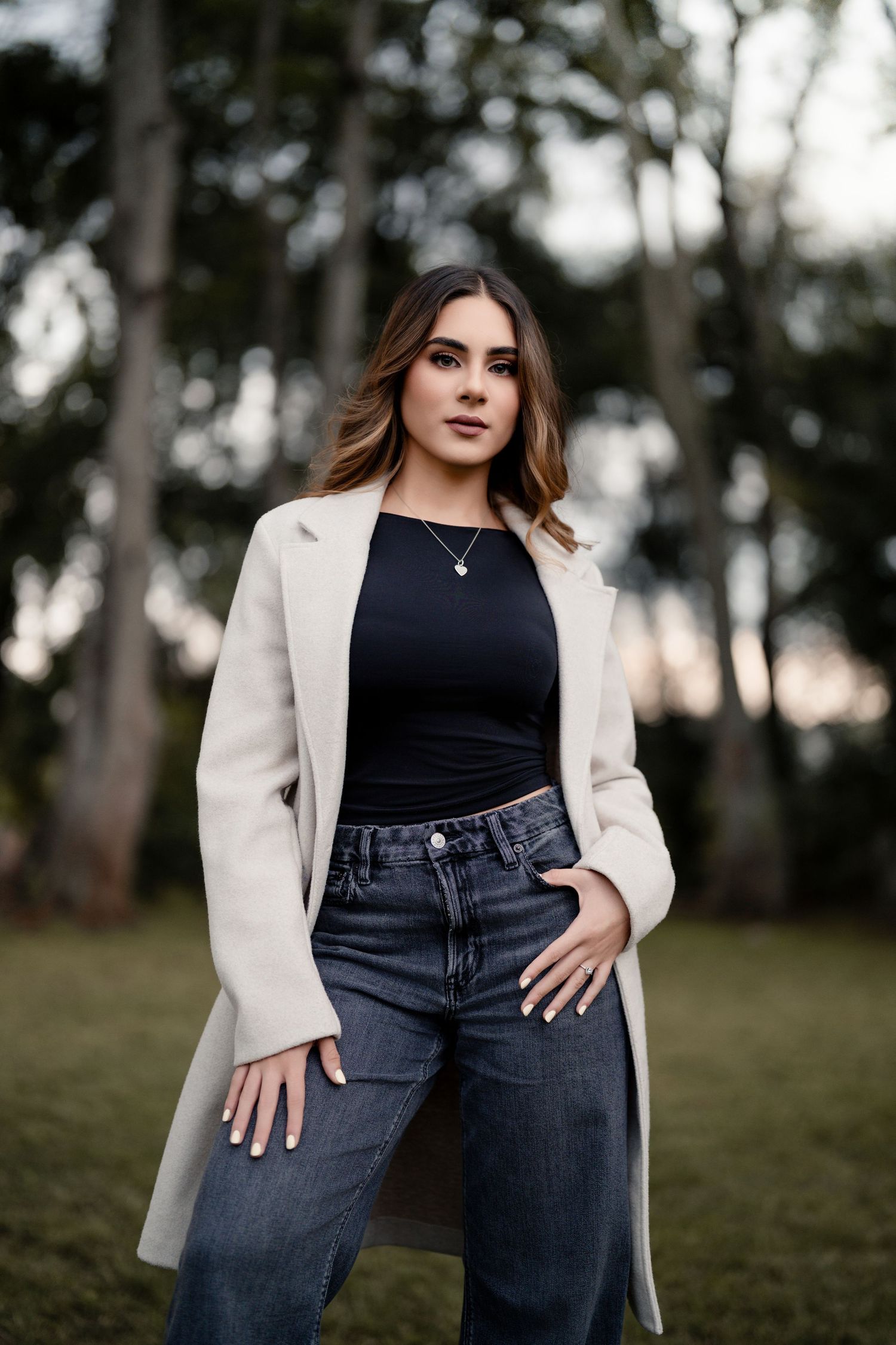 Casual fashion portraits featuring cream coat and dark denim in an outdoor setting.