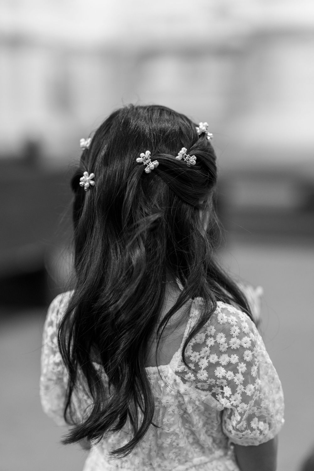 Back view of a child with dark hair wearing small white flower hair accessories.