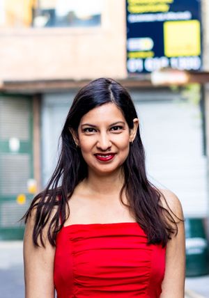 Portrait of someone wearing a vibrant red dress against an urban backdrop.