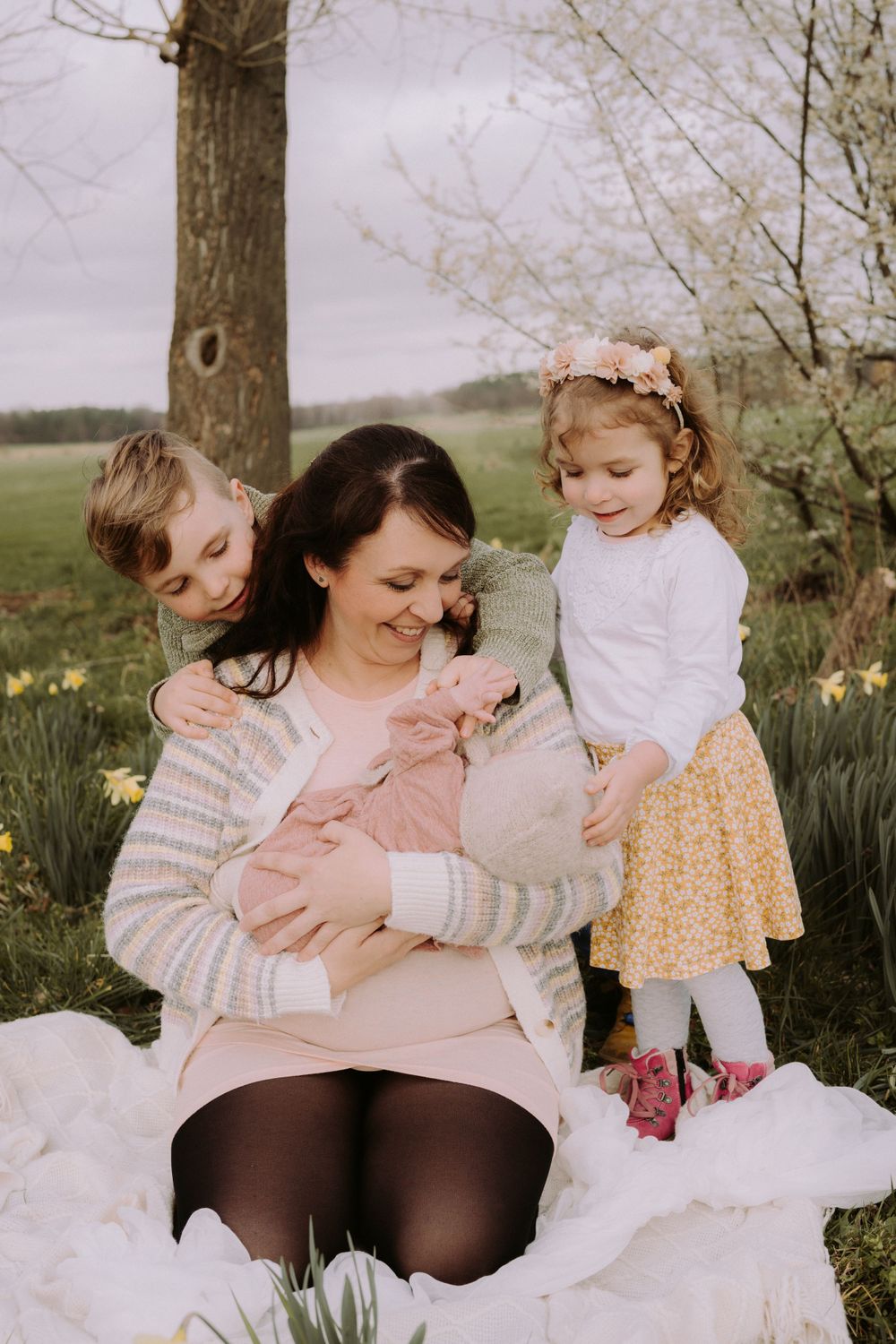 A touching family moment captured under spring blossoms with daffodils blooming in the background.