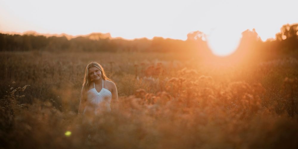 A golden sunset illuminates a field with tall grass and wildflowers during magic hour.