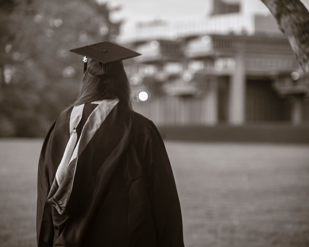 A cinematic black and white image of people in formal attire walking outdoors.