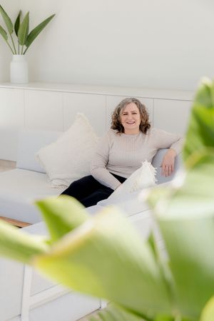 Cozy interior scene of white sofa with throw pillows and indoor plants in minimalist living space.
