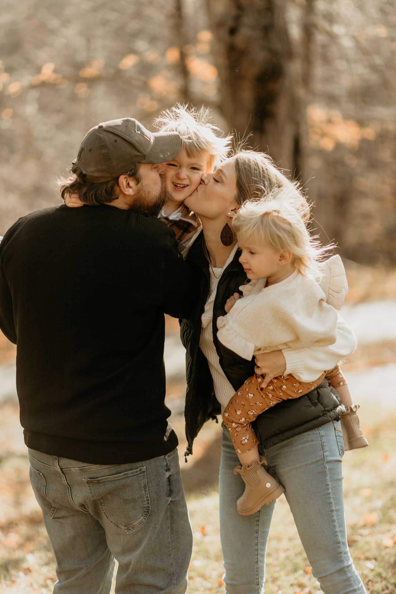 Sweet family moment captured in warm autumn light among fall foliage.