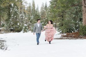 A couple running through snow-covered grounds in a winter wonderland setting.