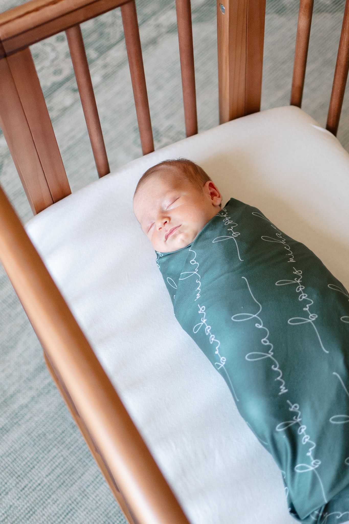 Newborn sleeps in his personalized swaddle at his newborn photo shoot in Winston-Salem.